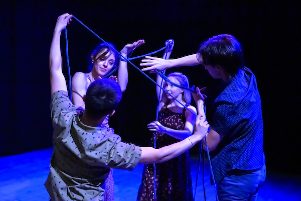 Four dancers manipulate yarn onstage.